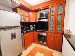 a kitchen with wooden cabinets and a stainless steel refrigerator at Precioso apartamento cerca del Aeropuerto de Bogta in Bogotá