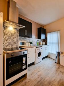 a kitchen with a stove and a washer and dryer at Cosy modern 1 Bedroom apartment! in Liverpool