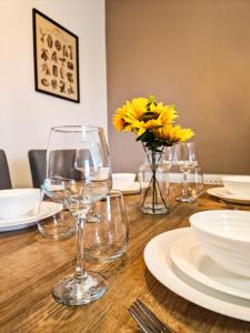 a wooden table with glasses and plates and yellow flowers at Cosy modern 1 Bedroom apartment! in Liverpool
