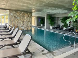 a hotel swimming pool with chairs and a stone wall at Hermoso y tranquilo departamento frente al mar. in Concón