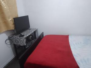 een slaapkamer met een bed met een rode deken bij Trinidad Hostal in San Salvador de Jujuy