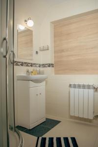 ein weißes Badezimmer mit einem Waschbecken und einem Spiegel in der Unterkunft Pokoje Gościnne Bożena Dunajczan in Brzegi