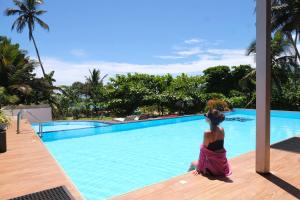 a woman sitting on a deck next to a swimming pool at BeachMirissa Hotel in Mirissa