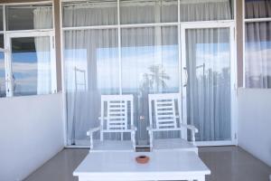 two white chairs sitting in a room with windows at BeachMirissa Hotel in Mirissa