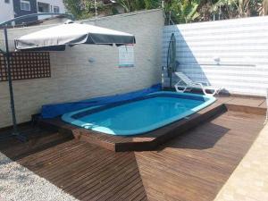 a swimming pool with an umbrella next to a wooden deck at Residencial Vovó Luiz in Florianópolis