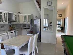 a kitchen with a table with chairs and a refrigerator at 芭提雅享受泳池别墅Enjoy Pool Villa in Pattaya South