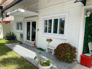 une maison blanche avec un banc dans la cour avant dans l'établissement 芭提雅享受泳池别墅Enjoy Pool Villa, à Pattaya (sud)