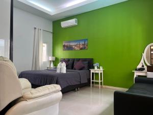 een groene slaapkamer met een bed en een bank bij 芭提雅享受泳池别墅Enjoy Pool Villa in Pattaya South