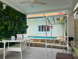 um pátio com uma mesa e cadeiras e uma piscina em 芭提雅享受泳池别墅Enjoy Pool Villa em Pattaya Sul