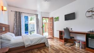 Dormitorio con cama, escritorio y TV en Coco Villa Ukulhas, en Ukulhas