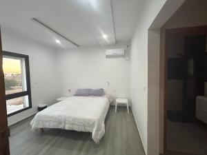 ein weißes Schlafzimmer mit einem Bett und einem Fenster in der Unterkunft Villa privé 4 chambres 4 lit double à Djerba en face de la ferme de lotos in Midoun