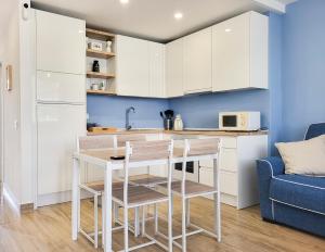 a kitchen with white cabinets and a table and chairs at Optimist las americas in Playa de las Americas