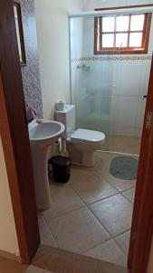 a bathroom with a toilet and a sink and a shower at Chácara Refúgio da Carol in Taubaté