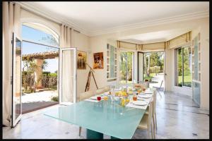 uma sala de jantar com uma mesa de vidro com cadeiras em LE CASTEL ROSE Super Cannes, face aux Îles de Lérins em Vallauris