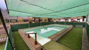 a large swimming pool with a green canopy at Modern Tiny Country House near Fataga & Maspalomas in Artedara