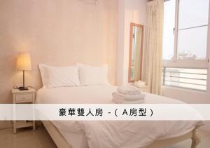 a bedroom with a white bed with a window at 在海的另一邊 in Anping