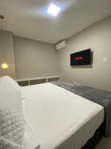 uma cama branca num quarto com um relógio na parede em Casa Amora em Arraial do Cabo