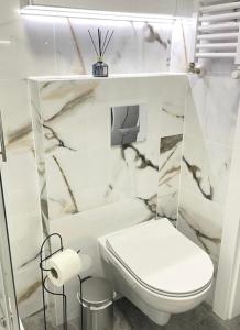 Łazienka z białą toaletą i marmurowymi ścianami w obiekcie New Classic Górne w mieście Piła