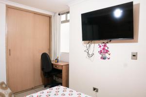 1 dormitorio con escritorio y TV en la pared en Elegante apartamento: Sabaneta Central, en Sabaneta