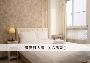a bedroom with a bed with white sheets and a window at 在海的另一邊 in Anping