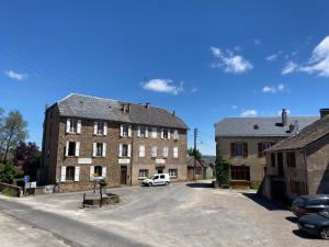 een oud gebouw met een auto geparkeerd op een parkeerplaats bij La Villa Bouloc, gite pour la famille in Salles-Curan