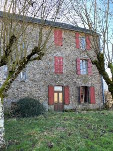 een oud stenen huis met rode deuren en ramen bij La Villa Bouloc, gite pour la famille in Salles-Curan