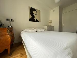 a bedroom with a white bed with a picture on the wall at Appartement la défense Courbevoie in Courbevoie