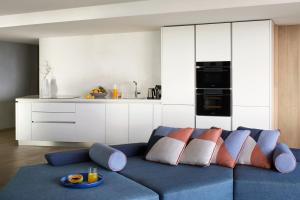 a living room with a blue couch and a kitchen at W Algarve in Albufeira