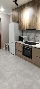 eine Küche mit einem Kühlschrank und einer Mikrowelle in der Unterkunft Квартира in Almaty
