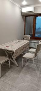 einen Tisch und Stühle in einem Zimmer mit Fenster in der Unterkunft Квартира in Almaty
