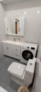 ein weißes Bad mit einem WC und einer Waschmaschine in der Unterkunft Квартира in Almaty