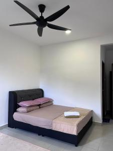 a bed with a ceiling fan in a room at Omak Kito Homestay Melaka in Kampong Alor Gajah