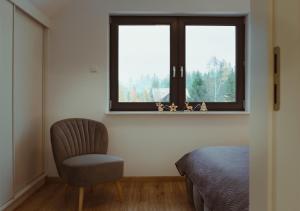 ein Schlafzimmer mit einem Stuhl und einem Fenster in der Unterkunft Domek na szlaku in Szklarska Poręba