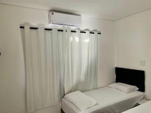 Habitación con cama con cortina blanca en Unidades mobiliadas em condomínio, en Lucas do Rio Verde
