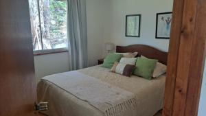 Un dormitorio con una cama con almohadas verdes y una ventana en Casa Algarrobo, en Algarrobo