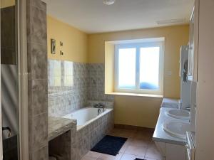 ein Bad mit einer Badewanne, 2 Waschbecken und einem Fenster in der Unterkunft charmante maison de campagne in Jonzac