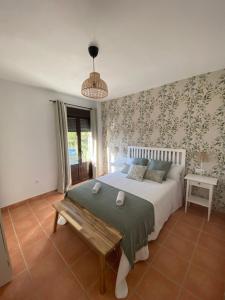 a bedroom with a bed and a bench in it at Alojamiento La Tana in Fuenteheridos