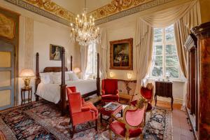 a bedroom with a bed and red chairs and a chandelier at Castello Di Casalborgone in Casalborgone