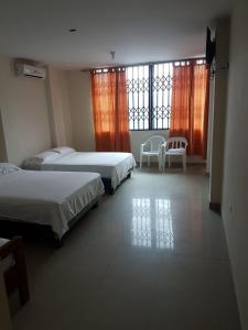 a bedroom with two beds and a table and chairs at El Sol Dorado in Tonsupa