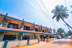 a building with a palm tree next to a street at Darsy Residency in Agonda