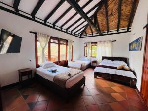 a bedroom with two beds and a large window at Cabaña Casa Cantabria in Villa de Leyva