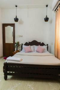 1 dormitorio con 1 cama grande con almohadas rosas en Kichu’s house, en Ernakulam