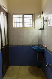 Kichu’s house في إرناكولام: حمام مع حوض أزرق ونافذة
