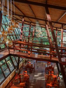 restauracja z drewnianymi stołami, krzesłami i oknami w obiekcie Ecoterra Inka Lodge w mieście Quillabamba