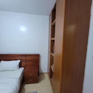 1 dormitorio con 1 cama y armario de madera en Unity Homes G en Eldoret