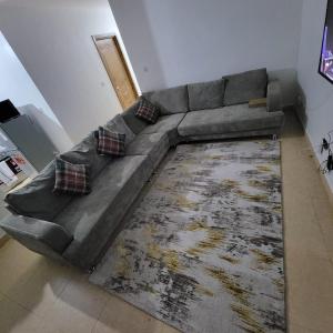 um grande sofá cinzento numa sala de estar com um tapete em Unity Homes G em Eldoret