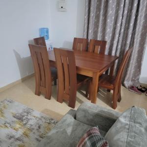 een houten eettafel met stoelen en een bank bij Unity Homes G in Eldoret