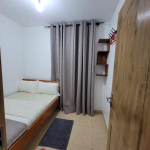 Habitación pequeña con cama y cortina en Unity Homes G, en Eldoret