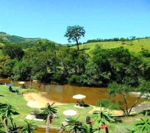 un gruppo di tavoli con ombrelloni accanto a un fiume di Estância Martins a Extrema