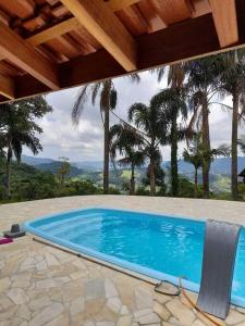 a blue swimming pool with a wooden roof and trees at Martins in Extrema
